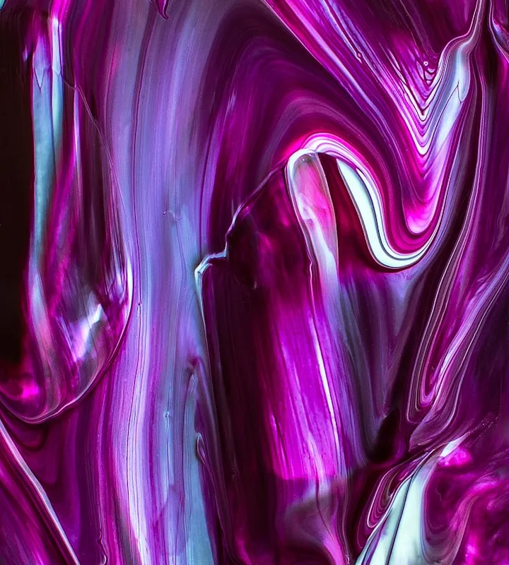 Macro of thick magenta, purple, and white paint swirled in a marbled acrylic-pour pattern