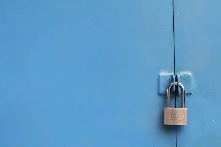 Silver padlock fastened through hasps on a light blue painted metal door