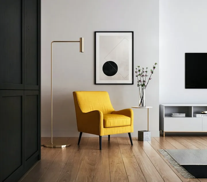 Bright yellow modern armchair in a minimalist living room with a brass floor lamp and geometric wall art