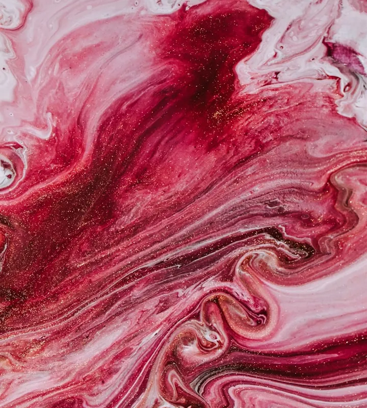 Abstract fluid painting with swirls of red, pink, and white paint and gold glitter