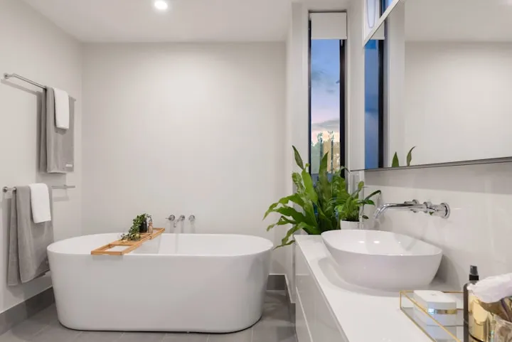 Bright modern bathroom with a white freestanding oval tub, vessel sink, and a large indoor plant